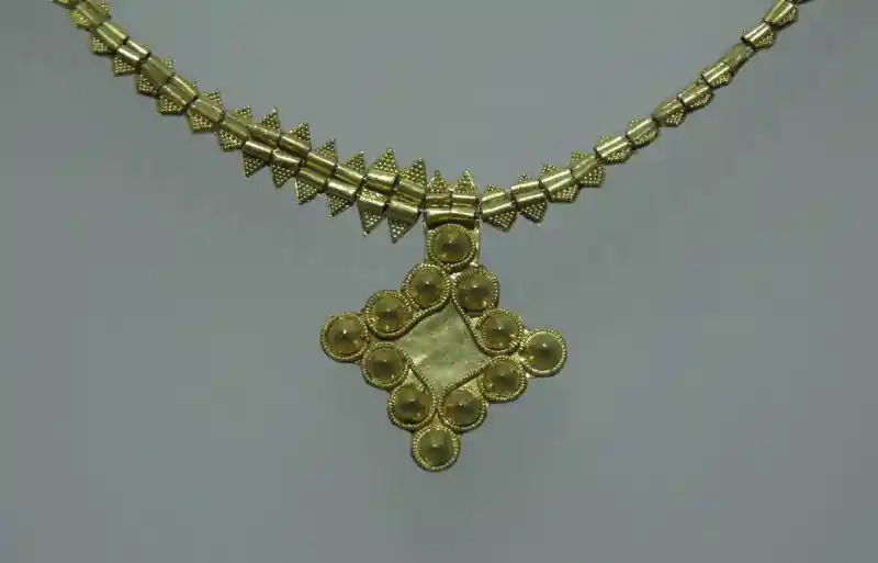 A gold necklace with a diamond-like cross pendant.